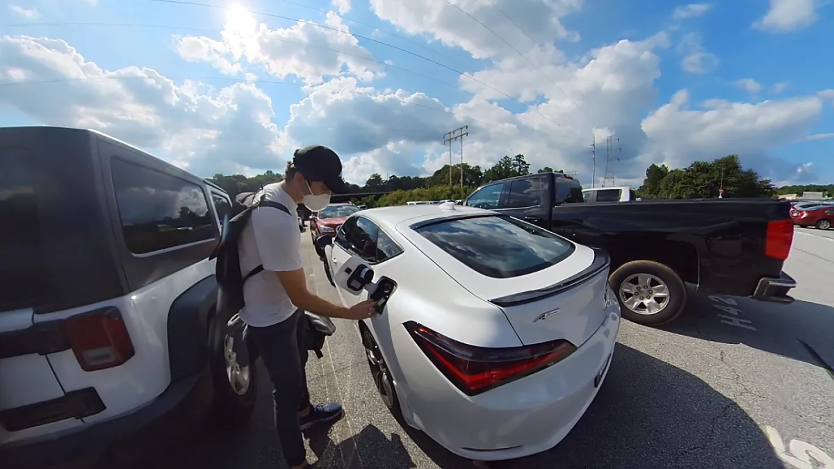 A researcher retrieves the car key from the fuel door at an off-site lot