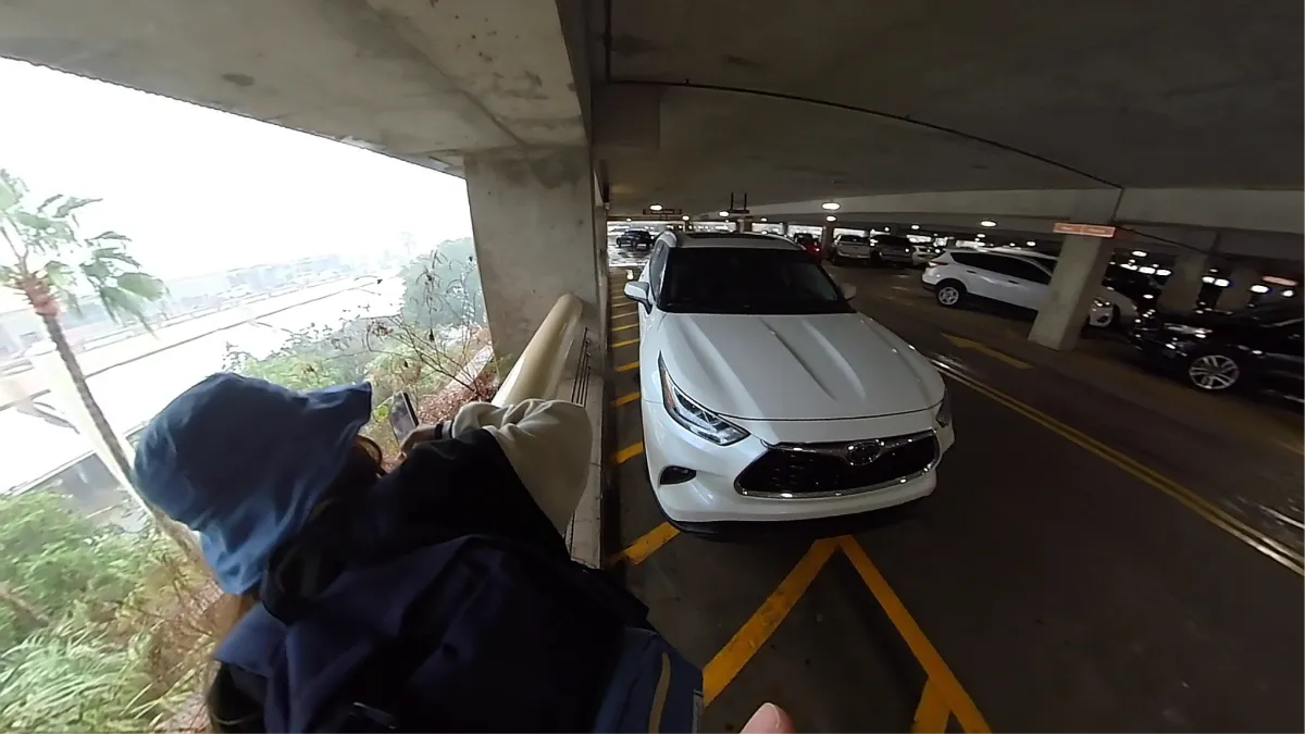 A researcher looks over a full airport parking garage in heavy rain during return